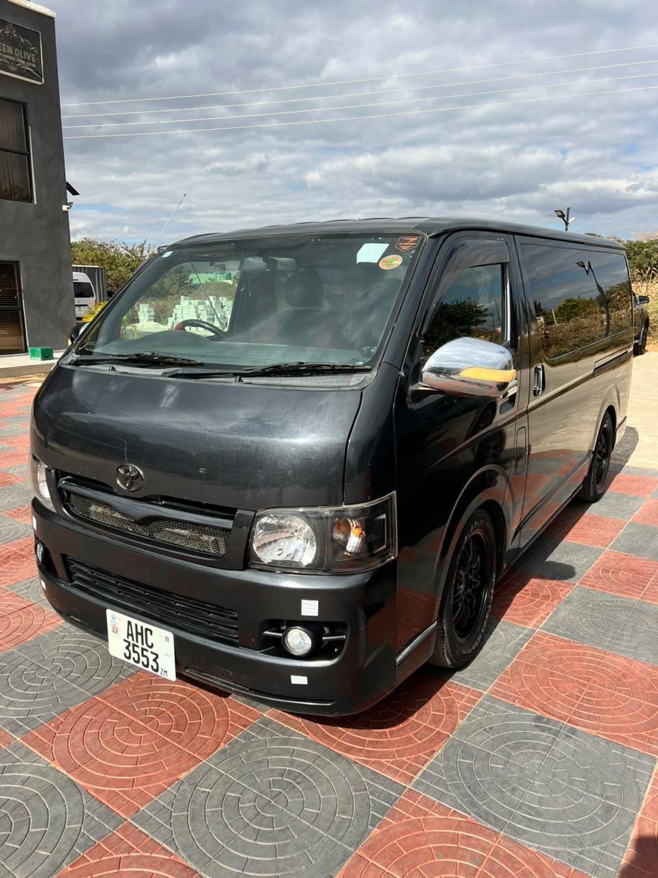 Front three-quarter view of the charcoal Toyota Hiace minibus in sunlight